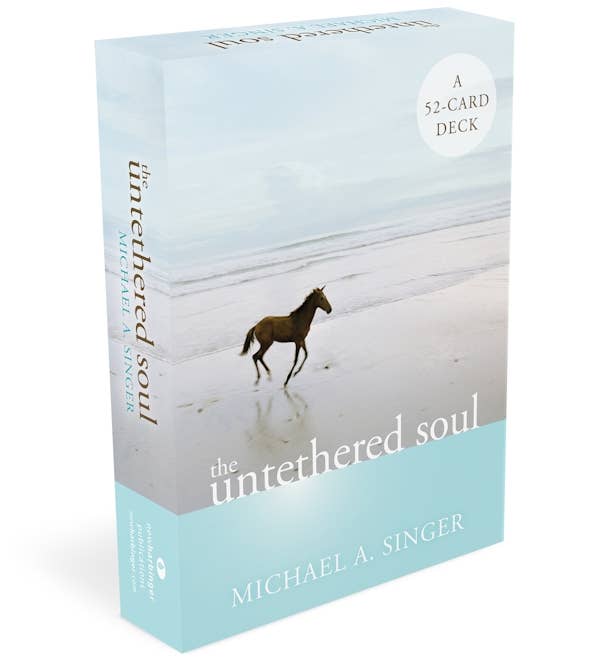 The Untethered Soul 52-card deck box by Michael A. Singer, featuring a light blue and gray cover with a horse walking on a beach.