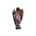 Rhodonite Crystal angel figurine on a white base with green plants in the background