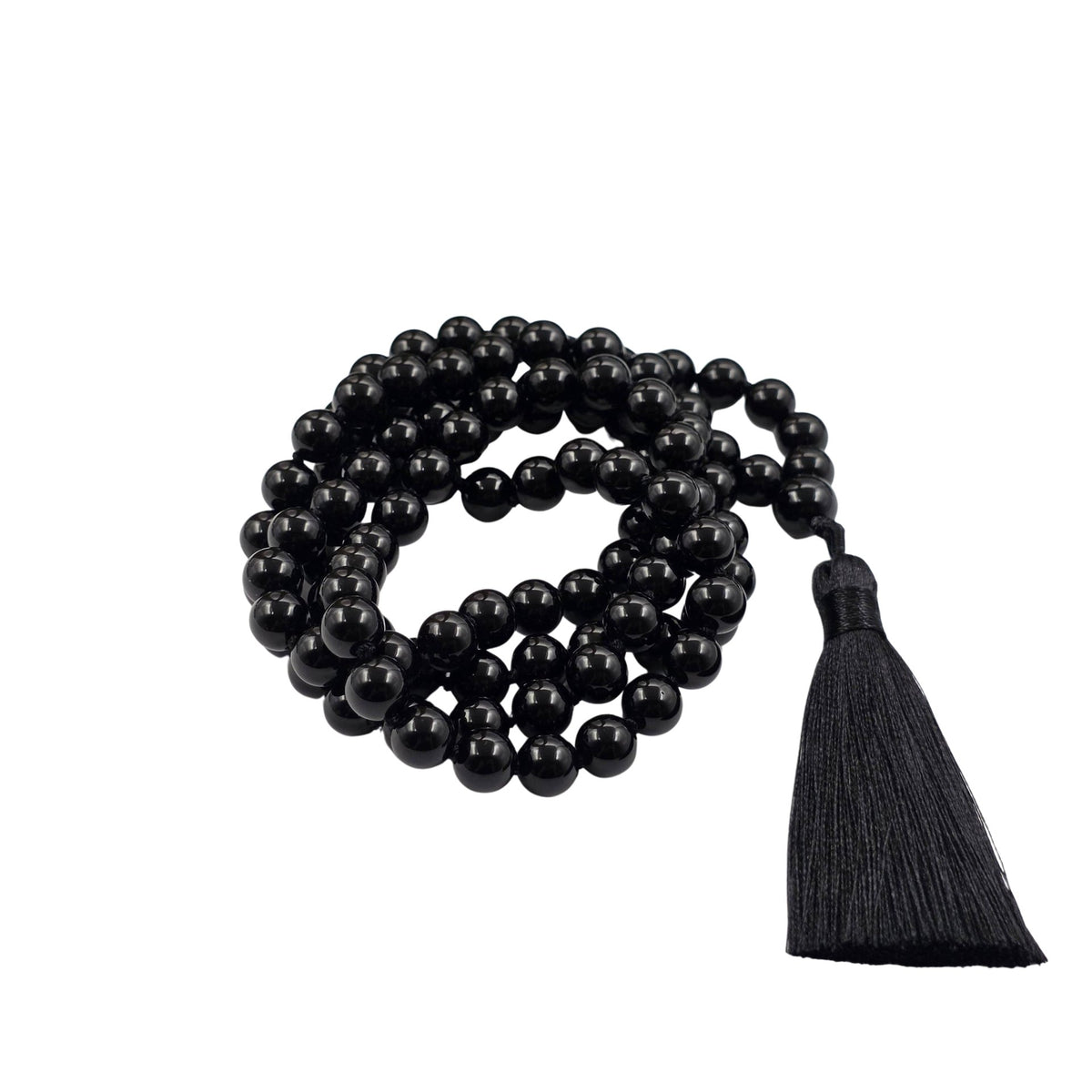 A black obsidian beaded necklace with a matching black tassel, arranged in a coil on a white surface 