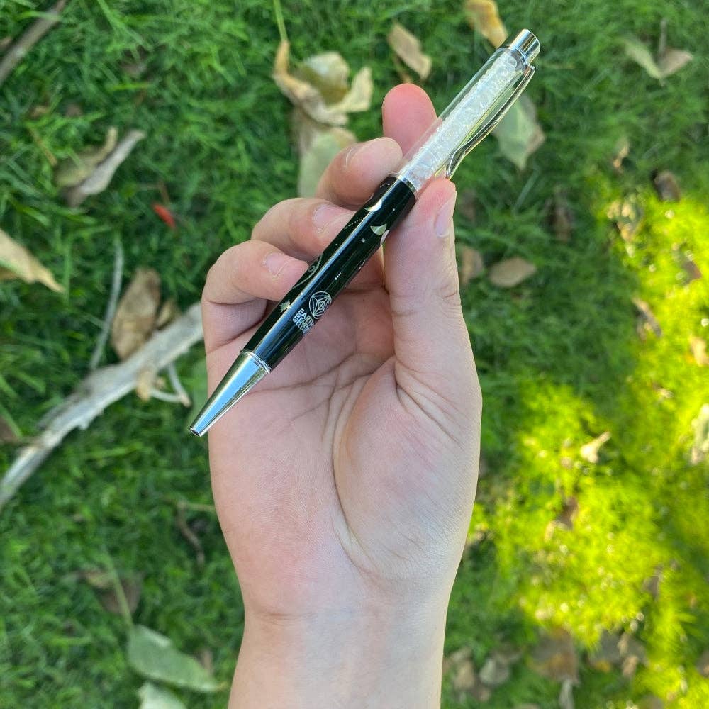 Hand holding a pen with a grassy background