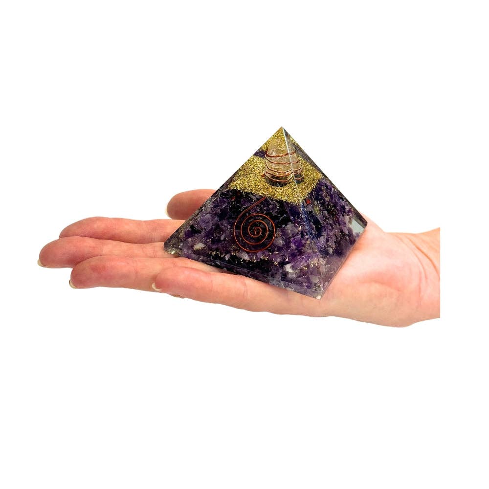 Amethyst Orgonite Pyramid-shaped crystal on a hand against a white background