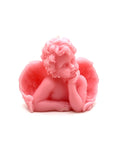 A pink cherub figurine with curly hair, angel wings, and a pensive pose, photographed against a plain white background.