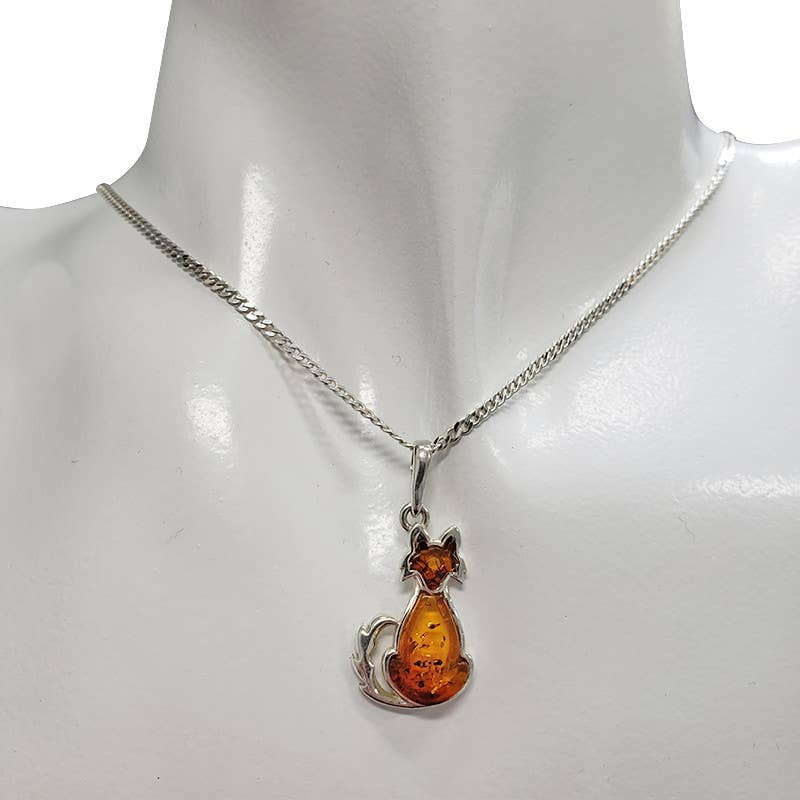 A silver-tone chain necklace with a cat-shaped amber pendant, displayed on a white mannequin bust.
