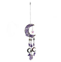 An amethyst crescent moon suncatcher ornament decorated with purple amethyst crystals, small metal moon phases, starbursts, and a dangling purple amethyst crystal bead, shown against a plain white background.