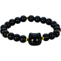 A black beaded bracelet featuring a central black cat-shaped bead with a hole, flanked by small gold spacer beads and round black beads with white star patterns.