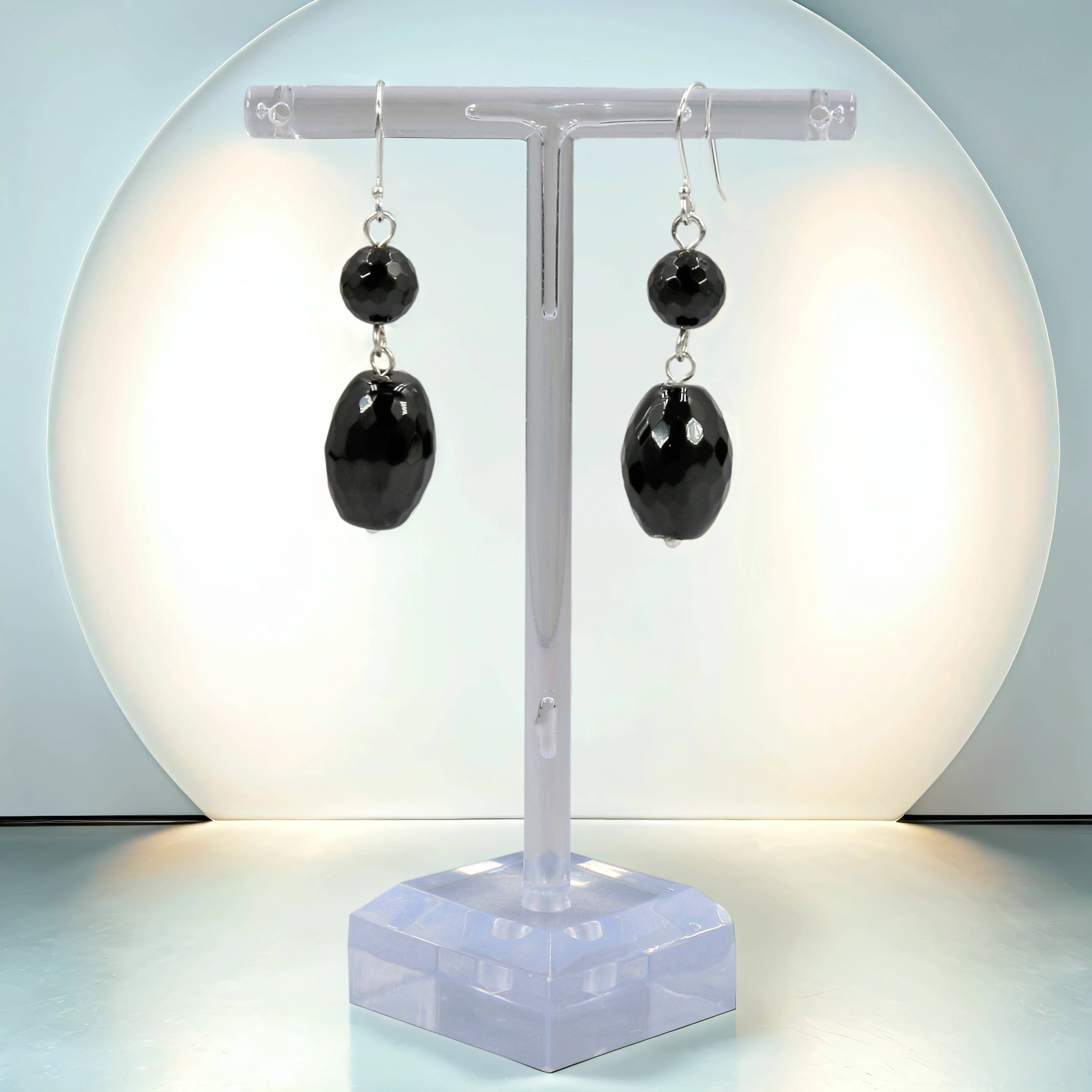 Black Onyx earrings on a clear stand with a light blue background