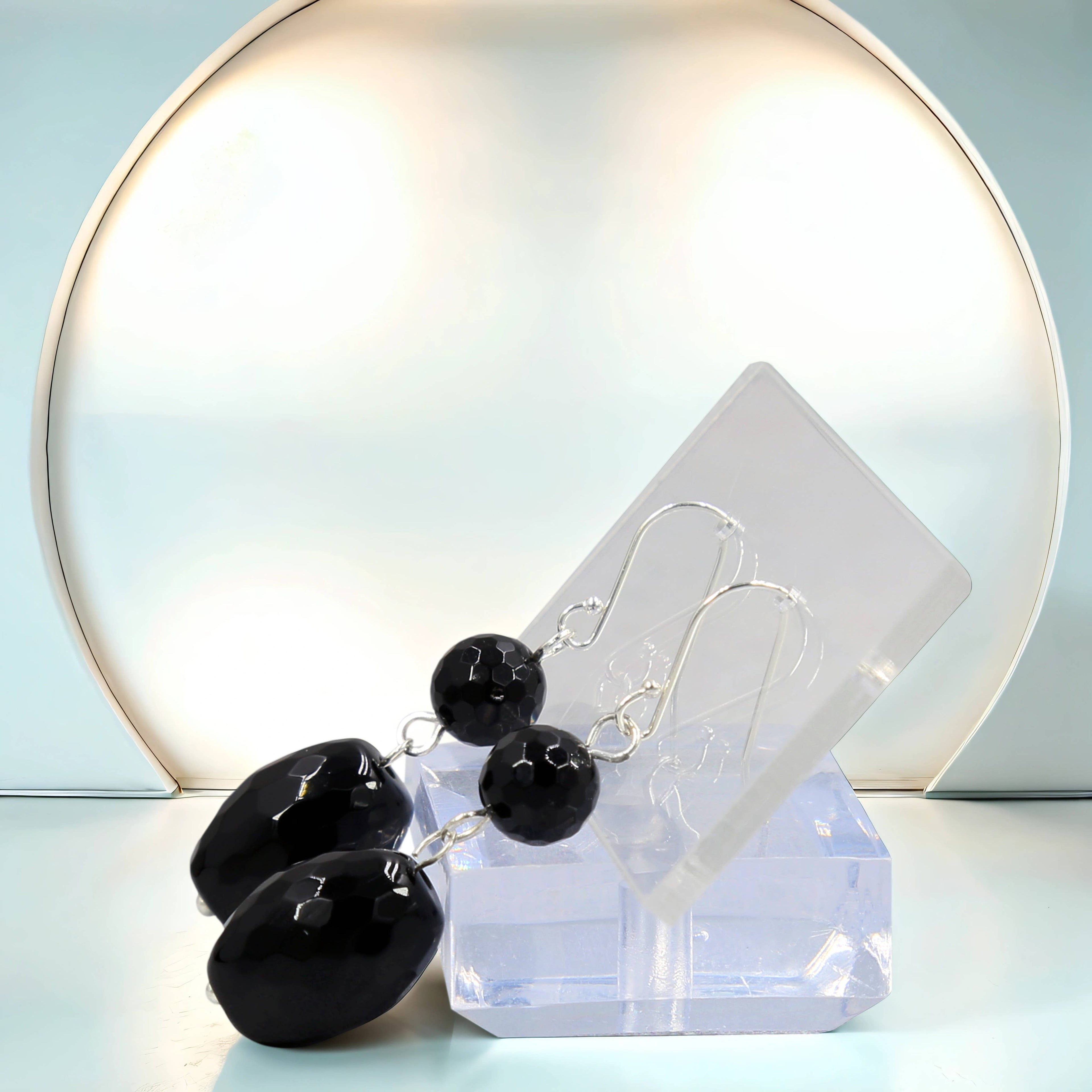 Black Onyx earrings on a clear stand with a light blue background