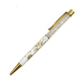 A white ballpoint pen with gold metallic accents, featuring a gold sunburst design and gold star details on a clear, glittery barrel, set against a plain white background.