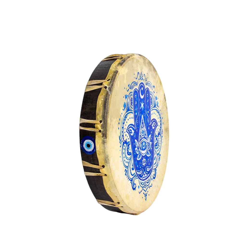 A hand drum with a beige drumhead featuring a blue hamsa hand design and evil eye motif, with a dark wooden body and gold-colored metal tuning rings, shown on a plain white background.