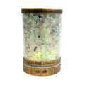 A cylindrical diffuser filled with multicolored Fluorite stones, featuring a rustic bronze-finished metal base and top, with a clear glass body showing the internal stone collection.