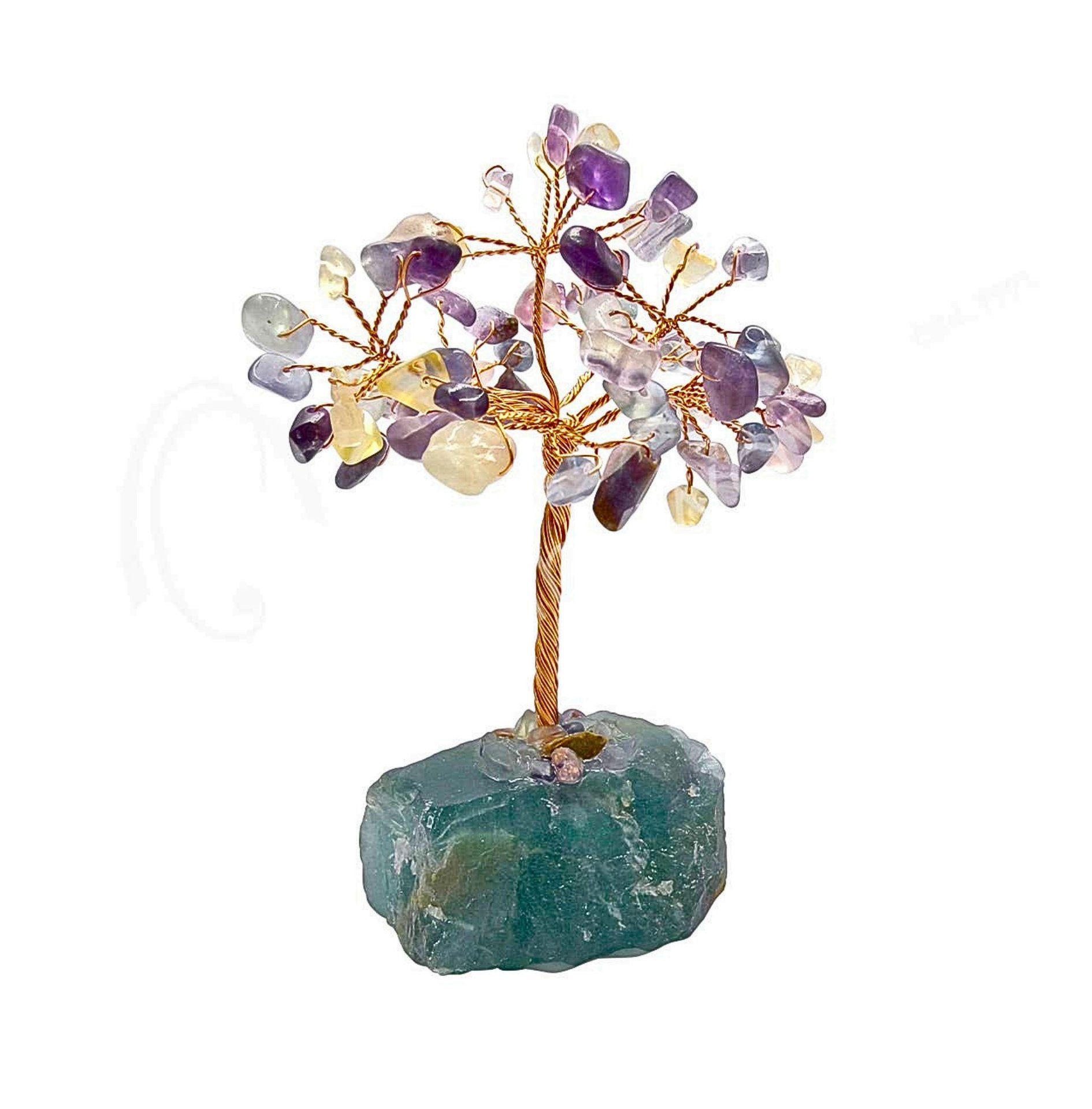 A fluorite crystal tree figurine featuring a twisted brown wire trunk and branches adorned with small purple, clear, and pale yellow amethyst stones, mounted on a dark green raw mineral base, shown against a plain white background. 63 beads