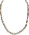 A strand of cream-colored freshwater pearls arranged on a white mannequin bust against a solid purple background.