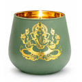 A green matte candle holder with a gold Ganesha design on the front, lit with a visible flame, set against a plain white background.