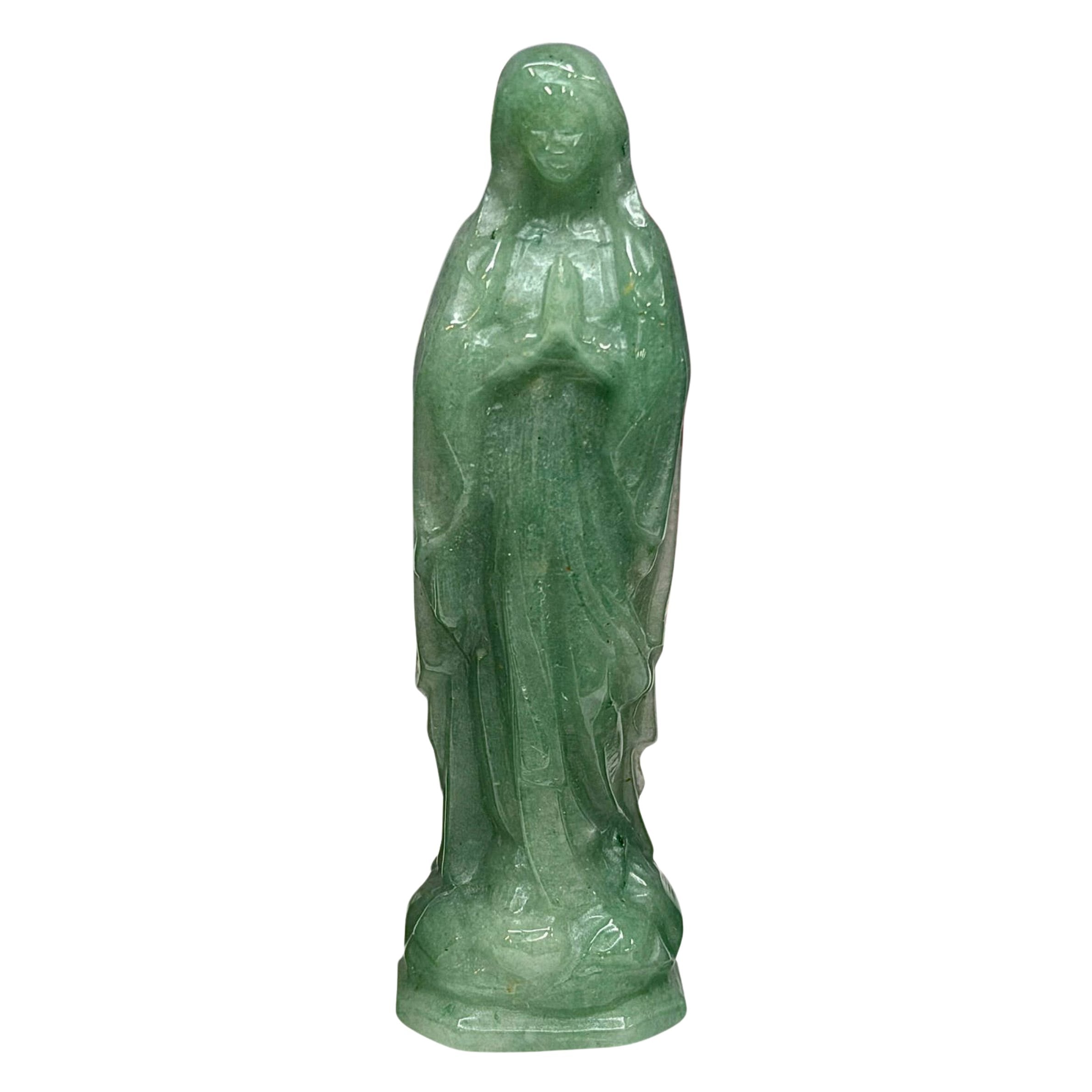 Three Green Aventurine Mother Mary Miraculous Medal figurines standing side by side on a white surface, with a purple background and decorative flowers behind and beside them. The text 'Aventurine' appears at the top.