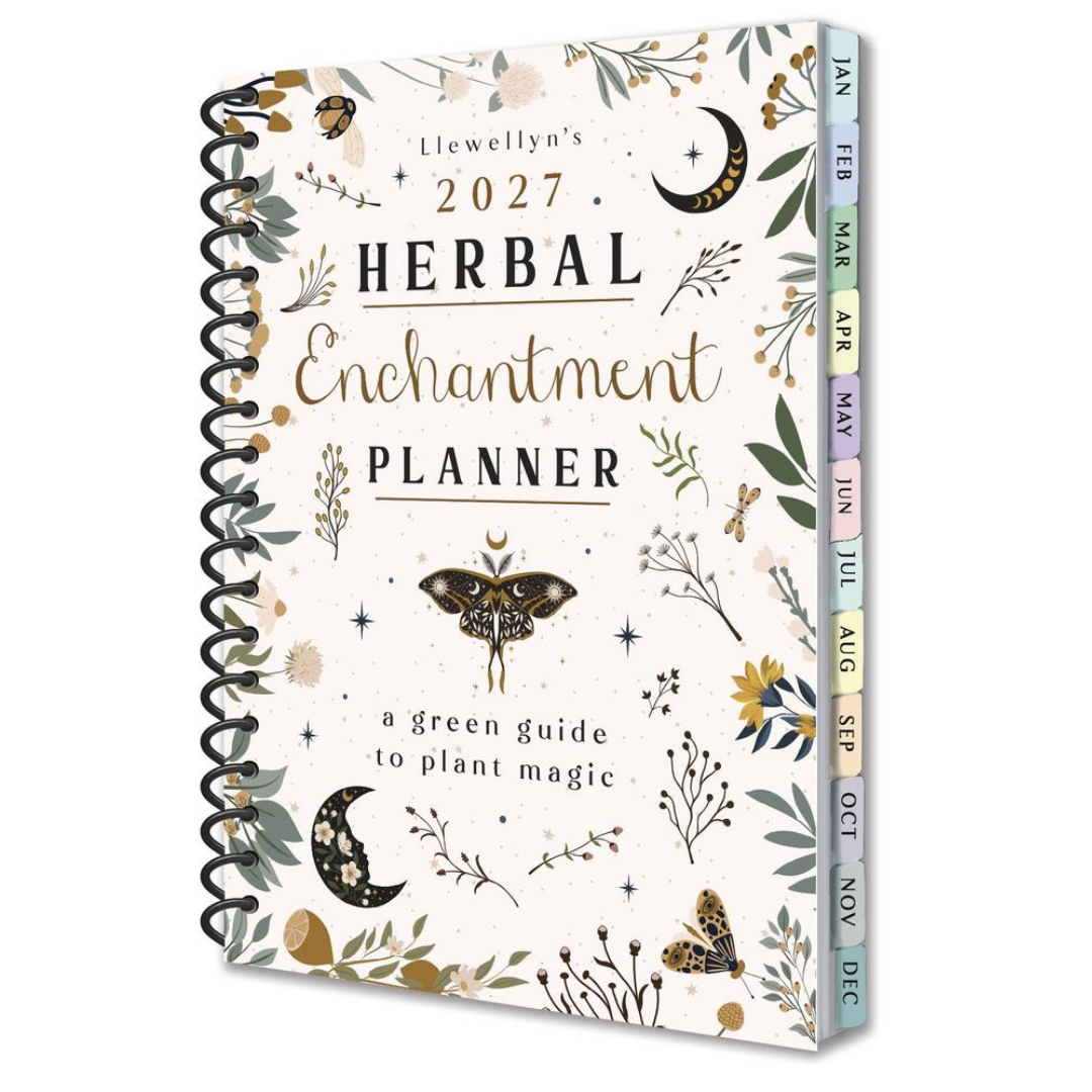 Llewellyn's 2027 Herbal Enchantment Planner, featuring a cream-colored cover decorated with botanical illustrations, a butterfly, crescent moons, and a black spiral binding. The colorful monthly tabs along the side are labeled for the months of the year.