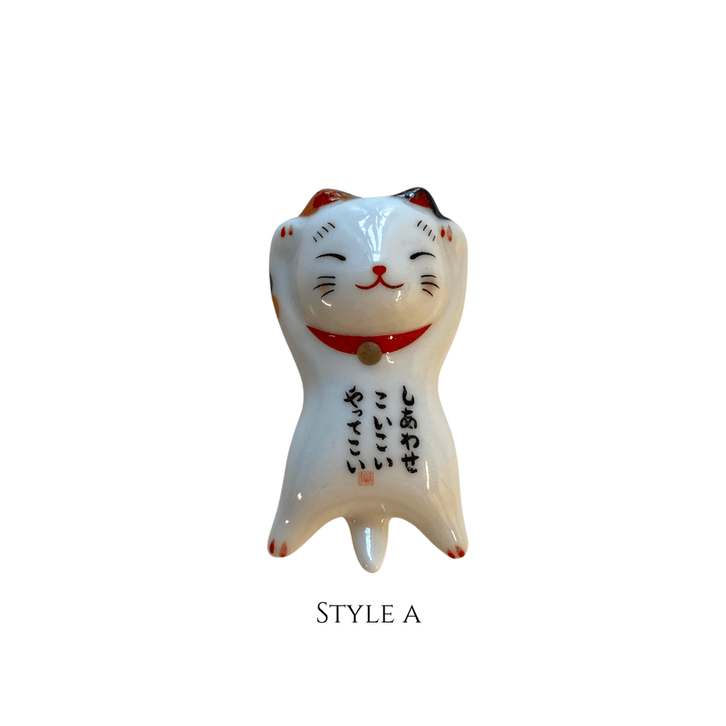 White ceramic cat figurine with red collar on a white background
