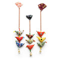 Three colorful fabric hanging ornaments with patterned triangular tassels and small bells, displayed against a plain white background.