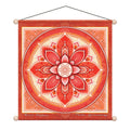 A square hanging wall tapestry featuring a red and orange mandala design with the words 'Root Chakra' and 'Tree Grounding' at the bottom, suspended by a black string from two wooden beads.