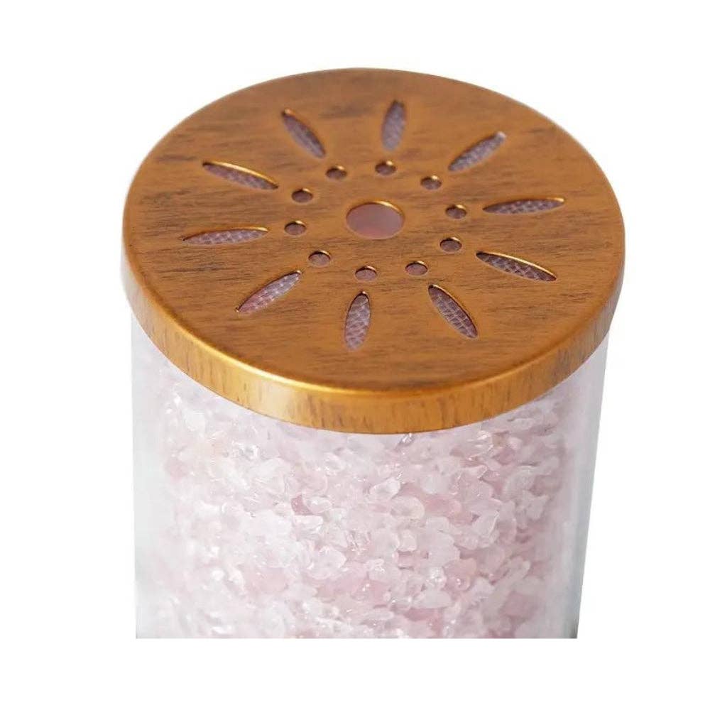 Clear container filled with pink Himalayan salt and wooden lid on a white background