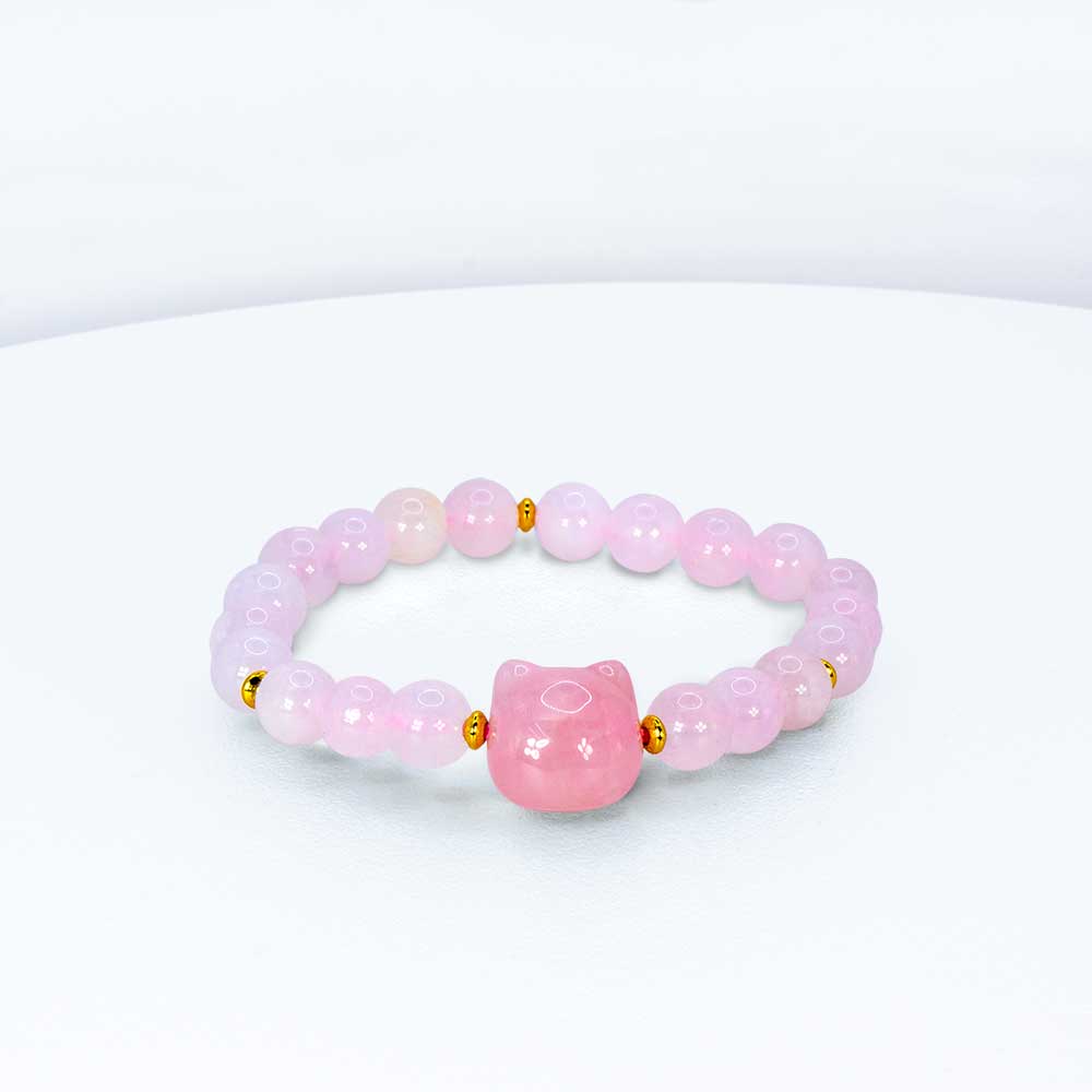 A pink beaded stretch bracelet featuring a central pink cat-shaped bead and small gold spacer beads, displayed on a clean white surface.
