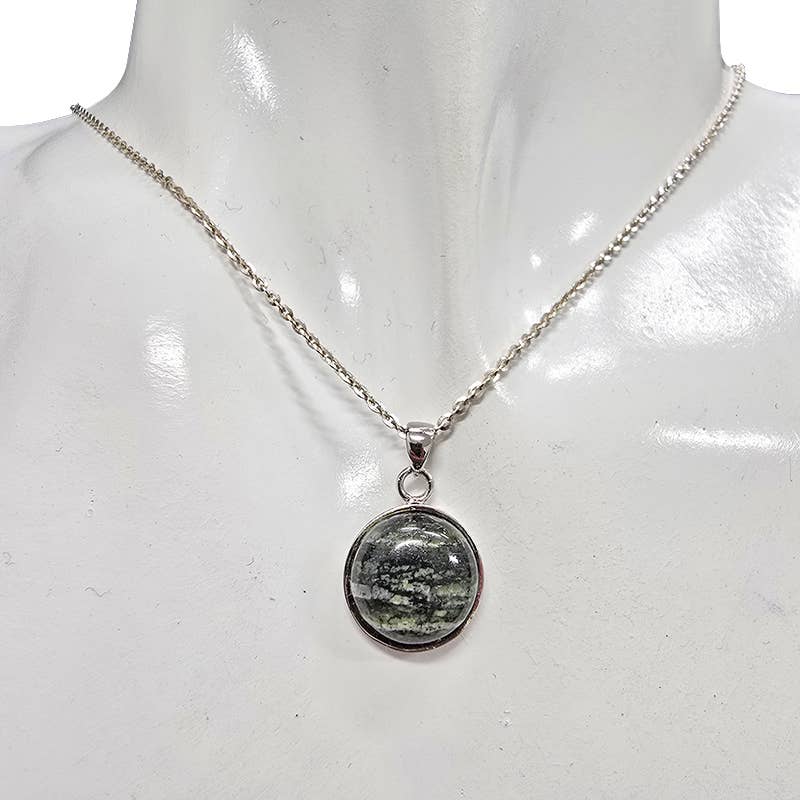 A silver chain necklace with a round pendant featuring a seraphinite stone, displayed on a white mannequin bust.