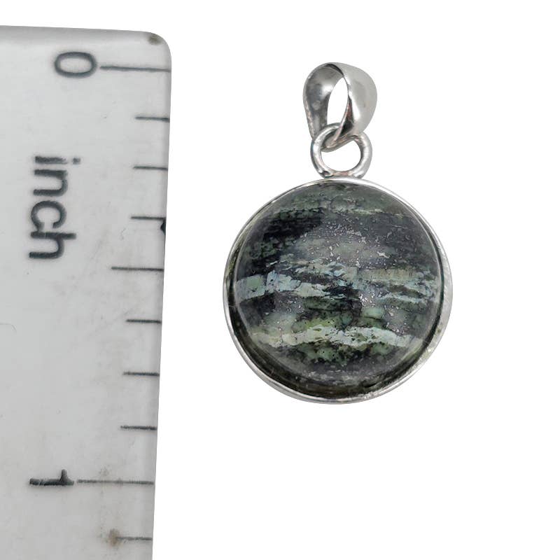 A silver pendant with a round cabochon Seraphinite, shown next to a white ruler for scale.