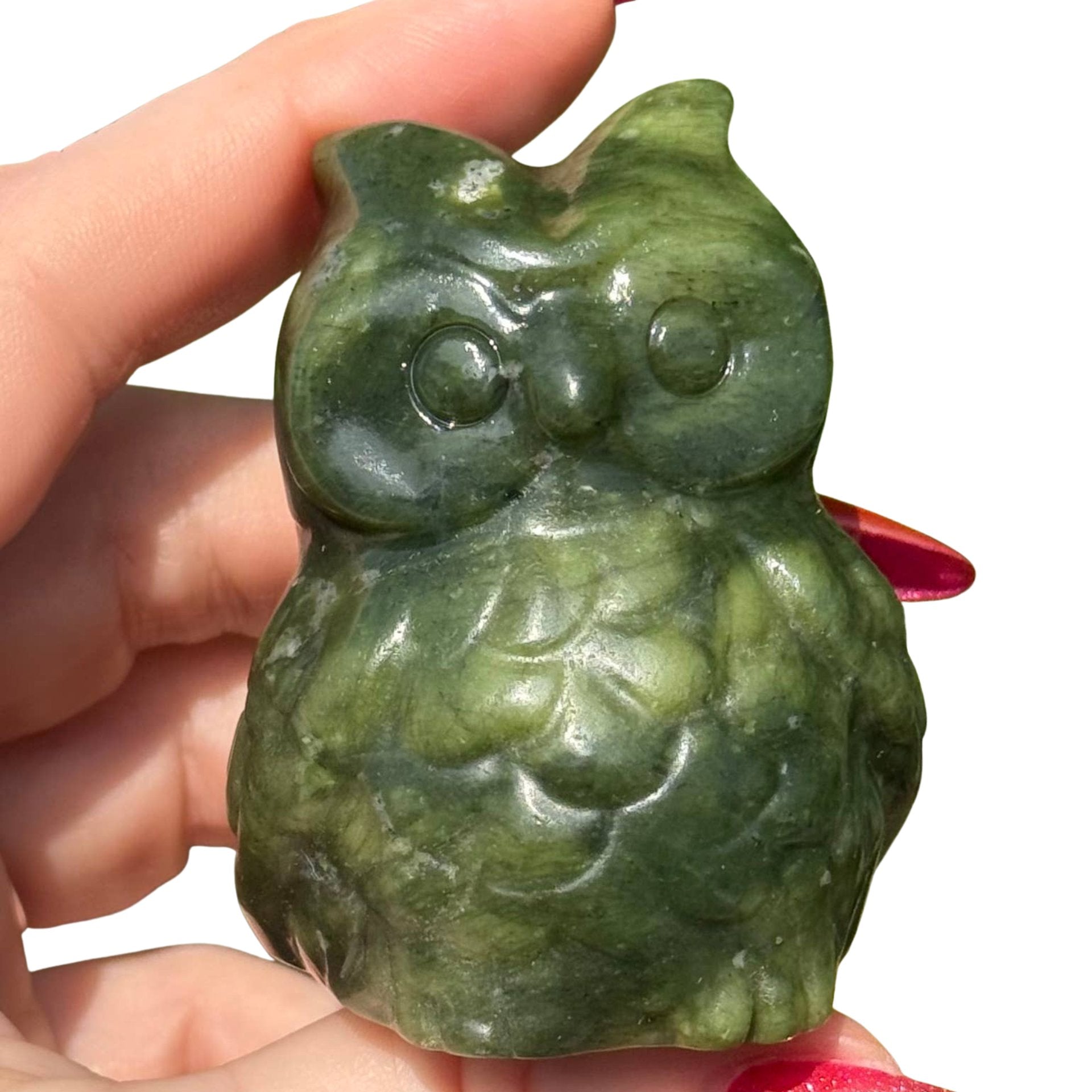 A hand holding a small carved green Serpentine owl figurine against a plain white background.
