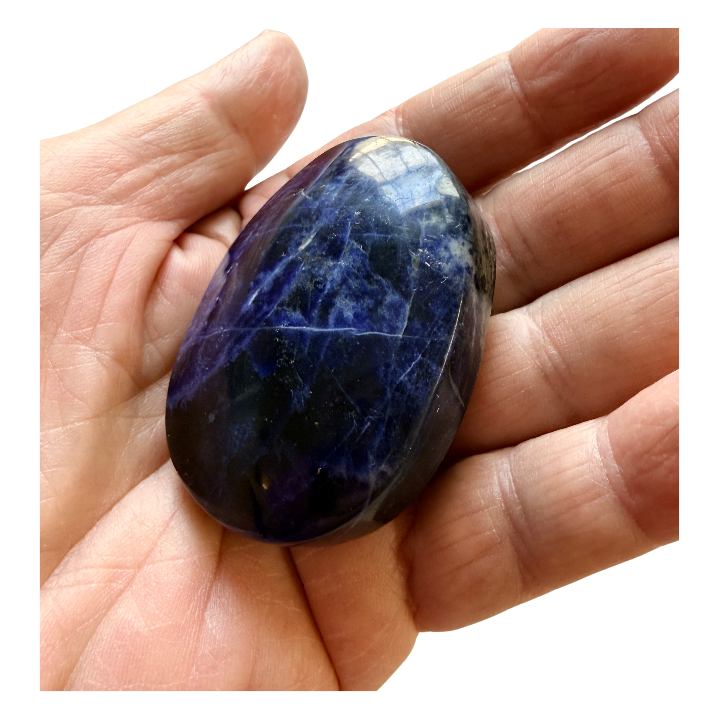 Hand holding a dark blue Sodalite Palm Stone  with visible veins on a white background