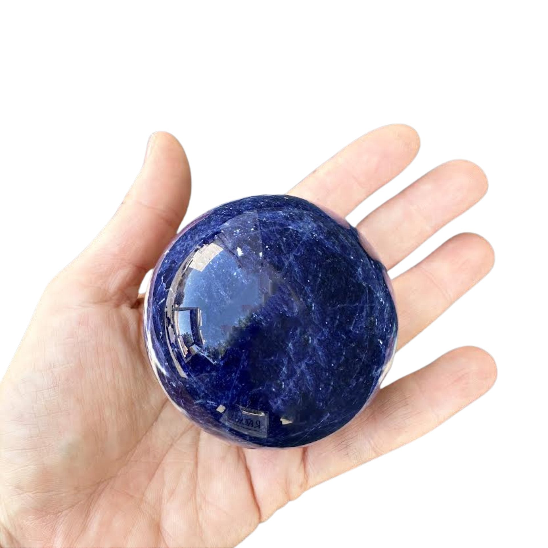 Hand holding a sodalite blue crystal ball against a dark background
