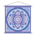 A square hanging wall tapestry featuring a detailed blue and white mandala design with a central geometric symbol. The tapestry has a purple border, decorative floral patterns, and wooden finials at the corners, suspended by a black string against a plain white background.