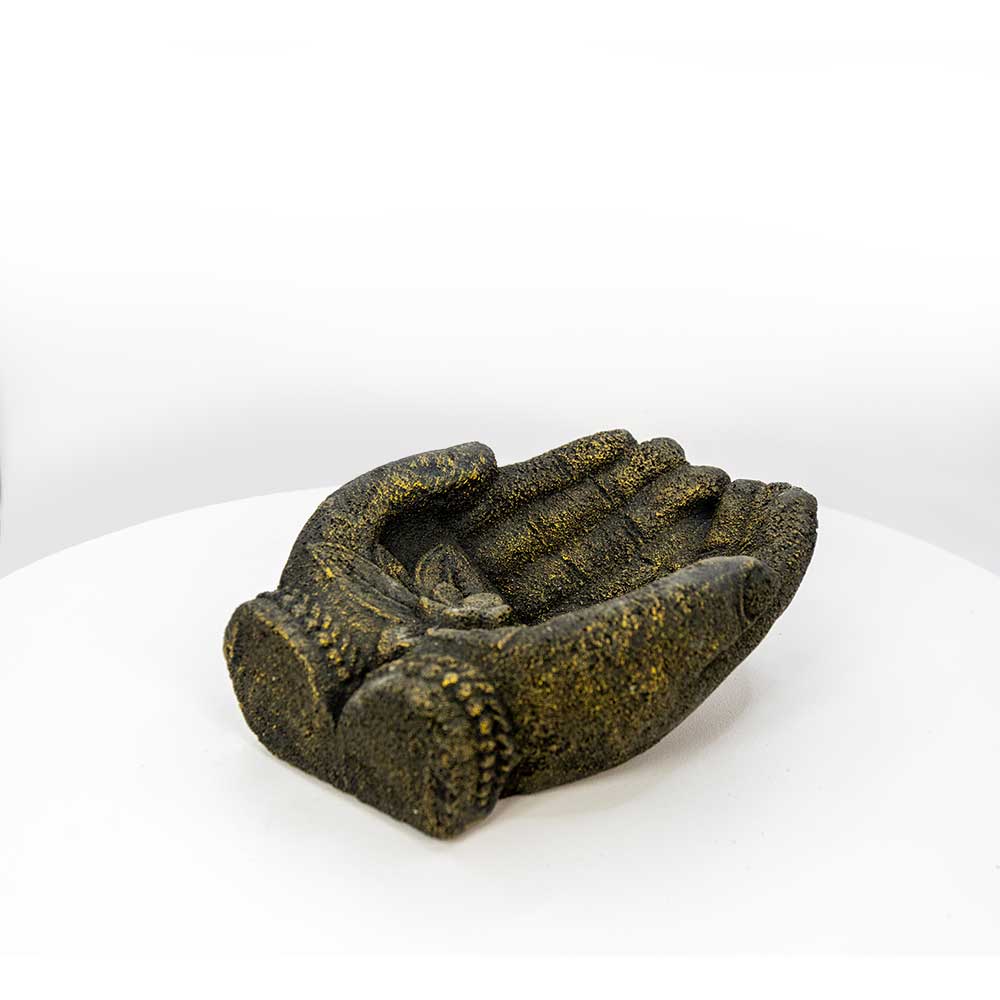 A small sculptural figurine of two praying hands in a dark olive-green and gold textured finish, displayed on a white circular platform against a white background.
