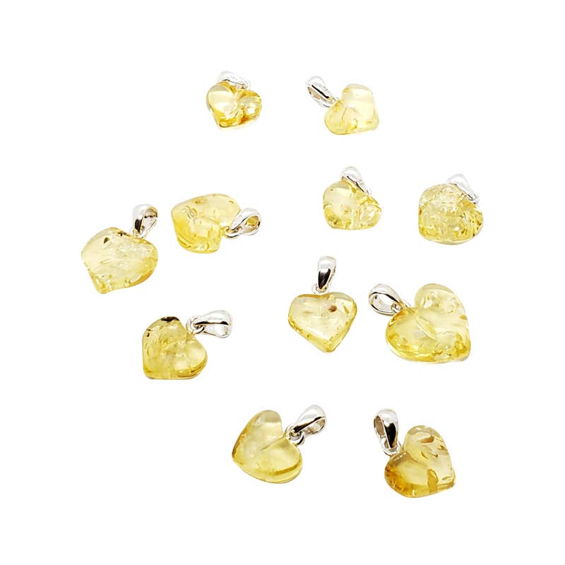 Ten small heart-shaped yellow amber pendants with silver bail loops, arranged on a plain white background.