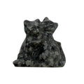 A carved stone figurine of two cats embracing, made from a speckled gray and white yooperlite stone, photographed on a plain light gray background.