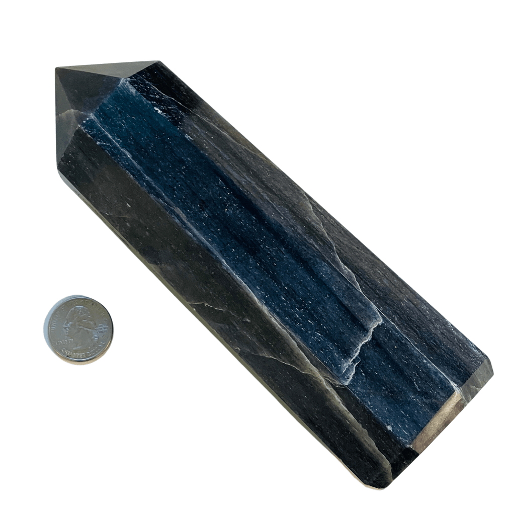 Blue crystal pyramid with a coin for scale on a white background