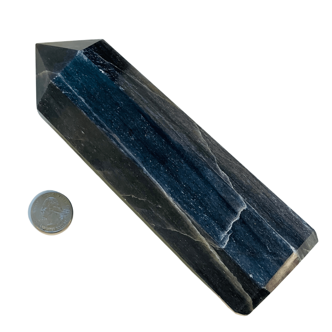 Blue crystal pyramid with a coin for scale on a white background