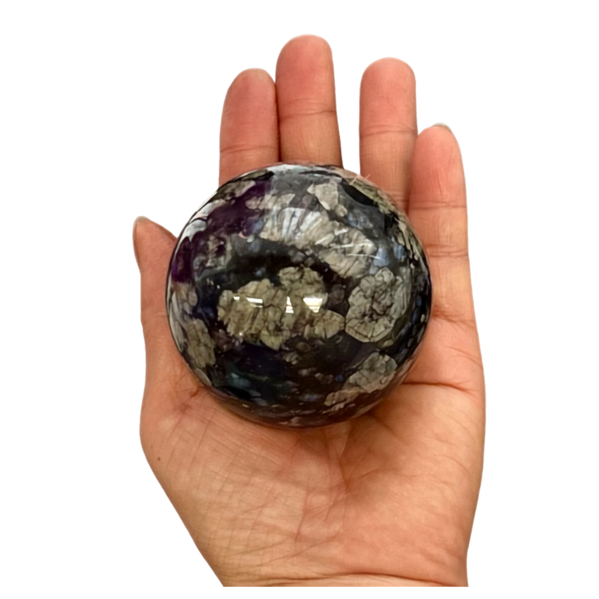 A polished round stone sphere with a marbled pattern of gray, white, and deep purple, held in the center of a person's open hand against a plain white background.