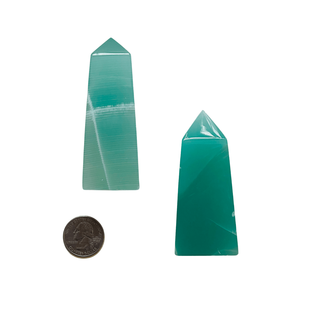 Two green crystal points with a coin for scale on a white background